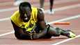 Usain Bolt makasi tuskissaan radan pinnassa Lontoon olympiastadionilla lauantaina.