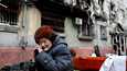 Iäkäs nainen istui pahoin tuhoutuneen asuintalon edessä Mariupolissa torstaina