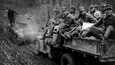Hyökkäysvaunu vetää rintamalla kuorma-autoa, jonka lavalla on sekaisin paikkakunnan asukkaita ja suomalaisia sotilaita. Kuvattu 20.9.1941.