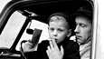 Alkuperäisen kuvatekstin mukaan tämä kuva on vuodelta 1958 osa kolmen kuvan sarjaa, jossa ”taksi oli kuljettamassa raajarikkoisia.” Kuvissa näkyy, että pieni poika ei itse polta tupakkaa, mutta aikuinen mies laittoi tupakan lapsen huulien väliin kuvaa varten.