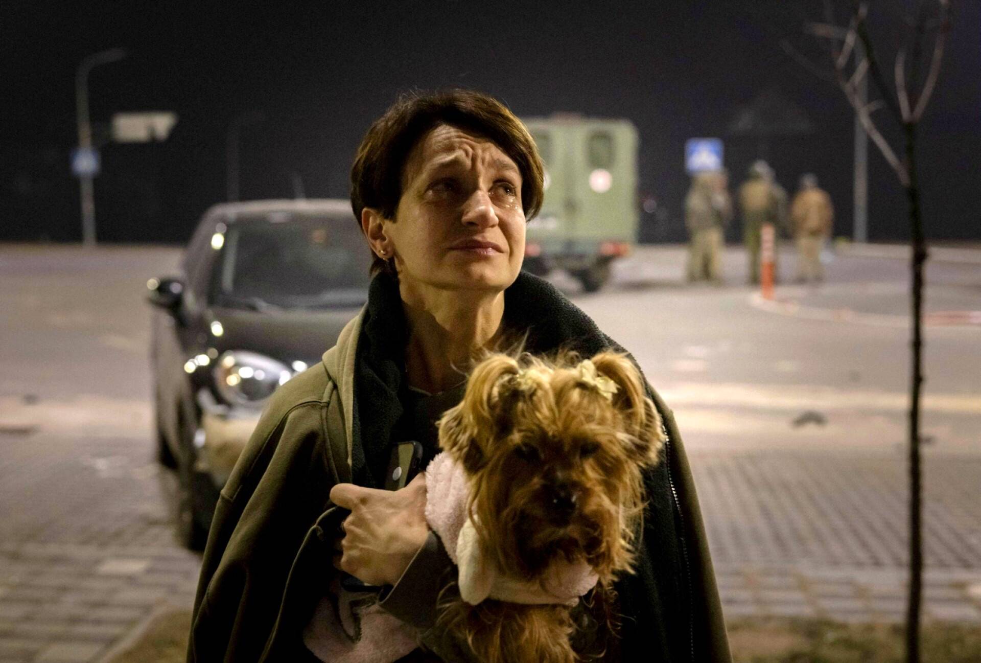 Koiraansa pitelevä nainen asuinrakennuksensa ulkopuolella Kiovassa.