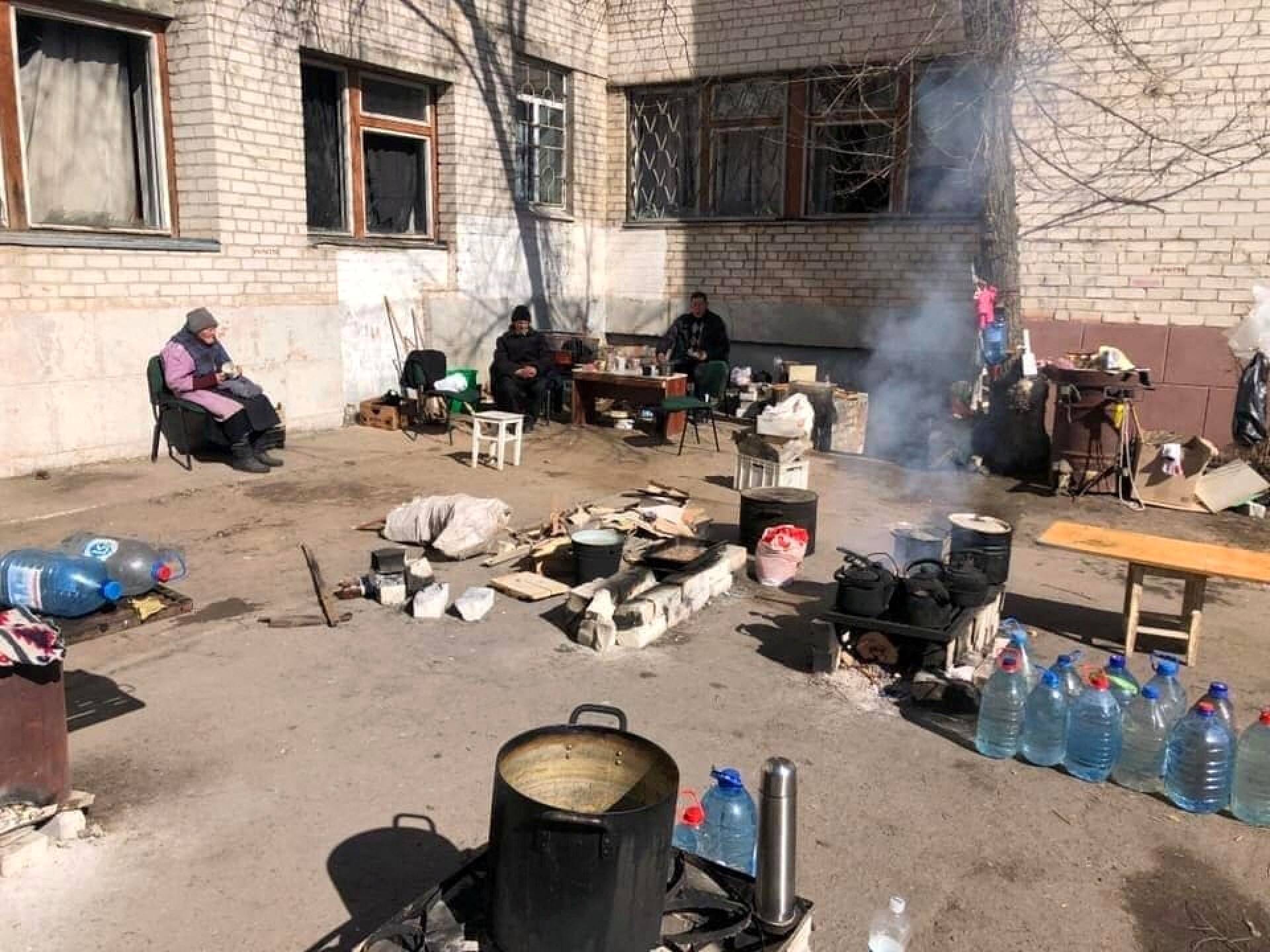 Ukrainalaisviranomaisten julkaisemassa kuvassa ihmiset tekevät ruokaa kerrostalon pihassa Luhanskin alueella. 