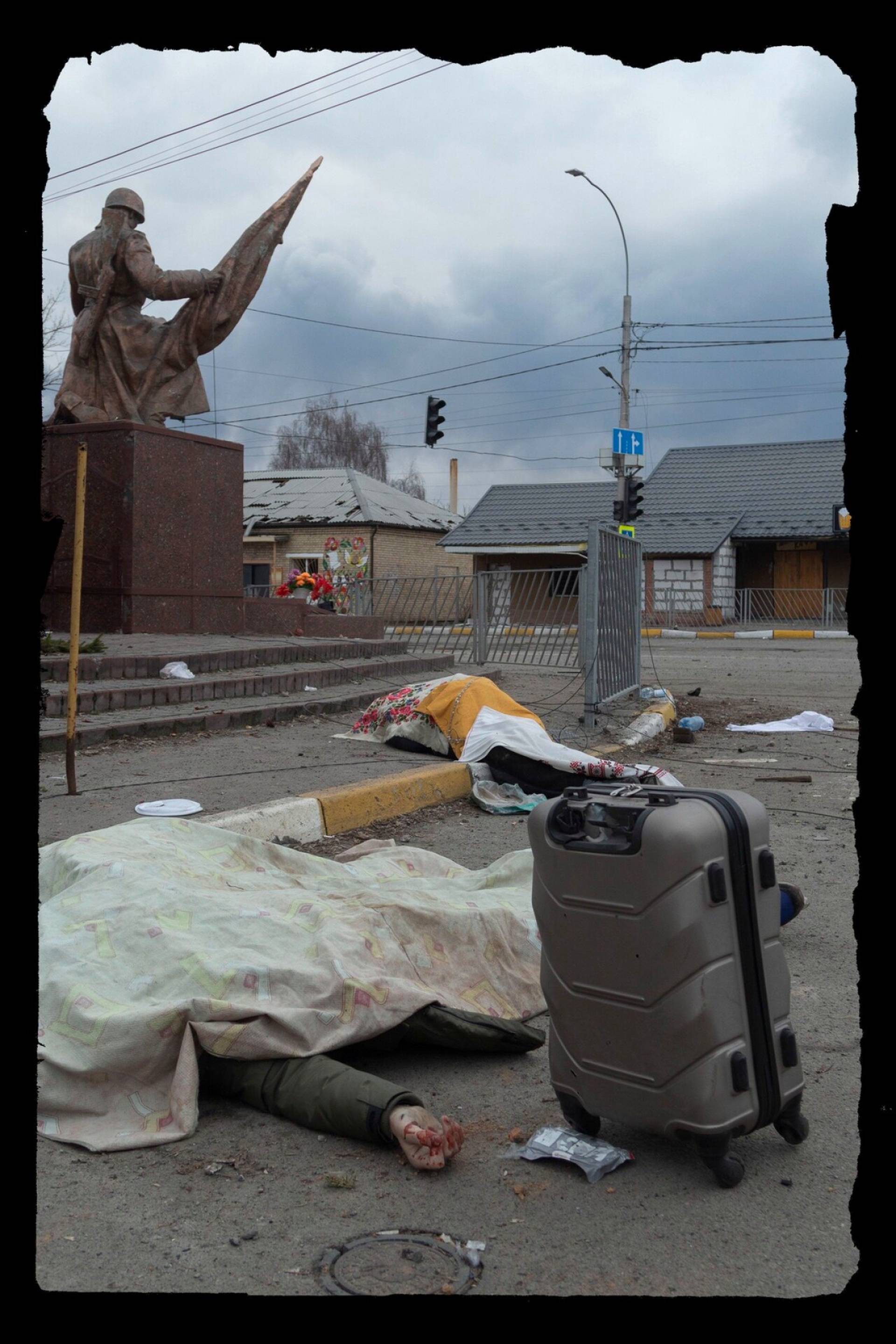 Тела  накрыты на месте смерти в ожидании вывоза. Статуя на заднем плане — памятник украинским героям, павшим в Великой Отечественной войне. 