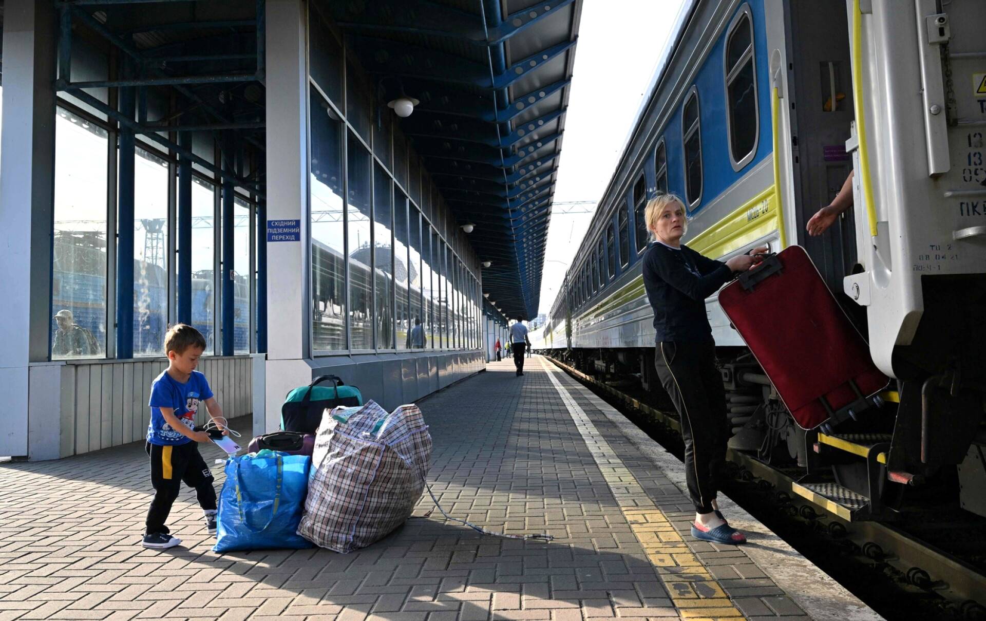 Nainen lapsensa kanssa purkaa matkatavaroitaan Puolasta Kiovaan saapuneesta junasta torstaina. Kasvava määrä sotaa paenneita ukrainalaisia on palannut tai palaamassa kotiseuduilleen.