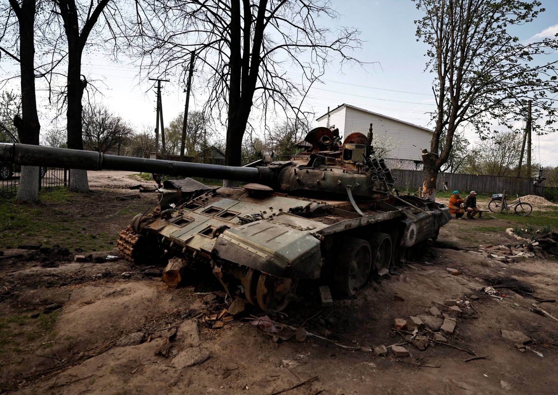 Ulyana Pishchur, 72, istuu penkillä tuhotun venäläisen tankin takana Slobodassa Tshernihivin alueella.