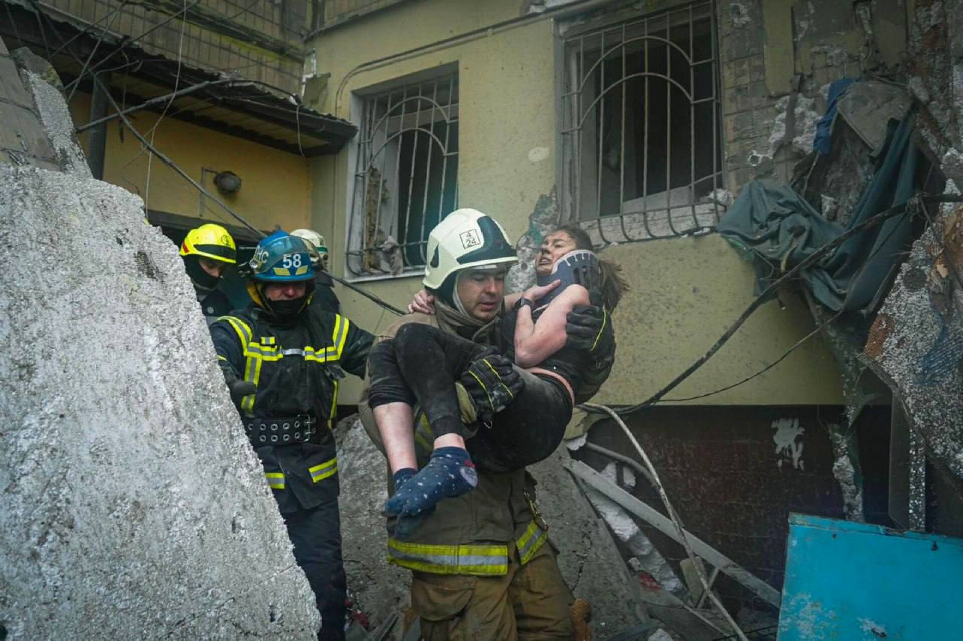 Maa täynnä raunioita. Ukrainalaiset pelastustyöntekijät veivät iäkkään naisen turvaan Venäjän tykkitulen tuhoamalta asuinalueelta Dniprossa viime tammikuussa.