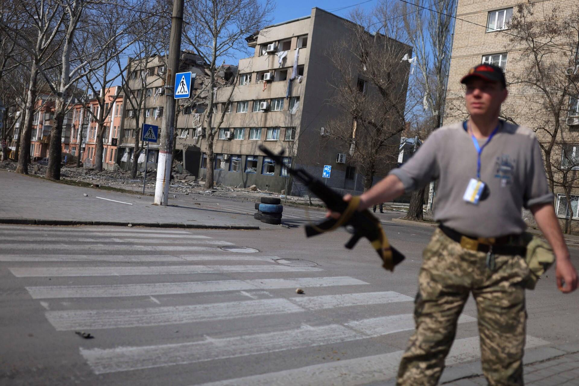 Ukrainalaissotilas aseineen Venäjän iskun vaurioittaman rakennuksen lähellä Mykolajivissa maanantaina.