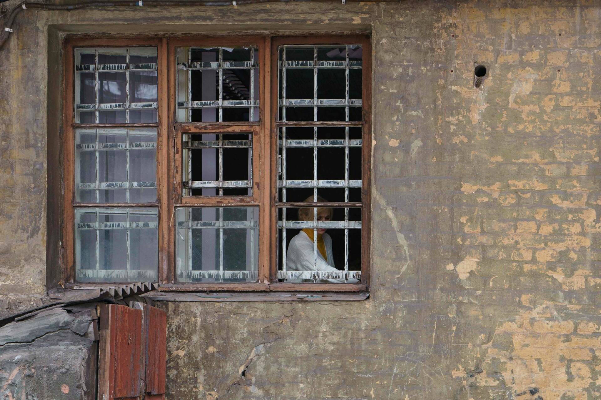Nainen ikkunassa Dniprossa. Asuinrakennus vaurioitui Venäjän hyökkäyksessä.