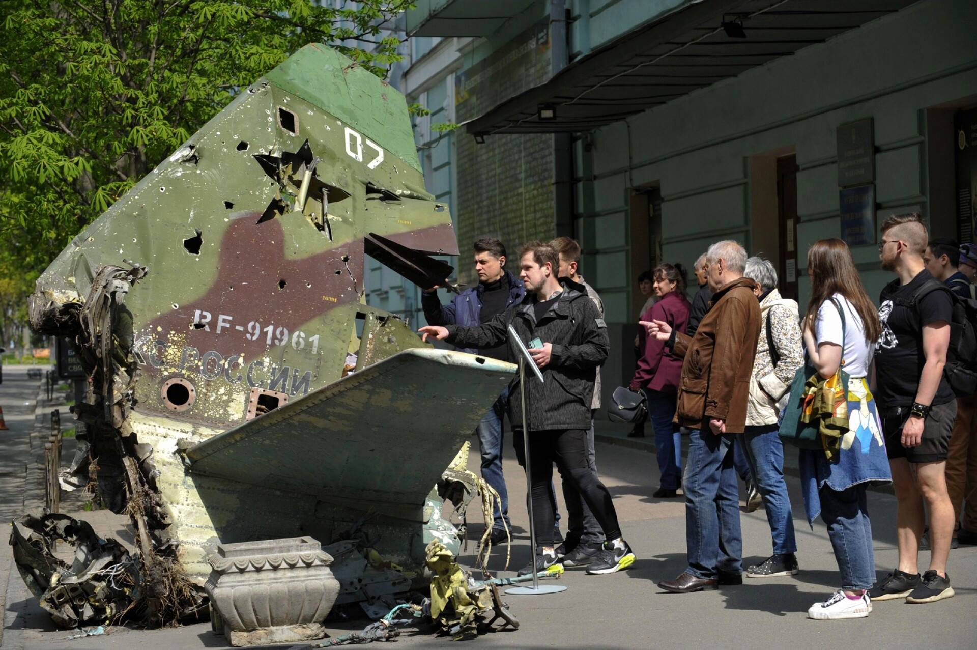 Ihmiset tutkivat tuhoutuneen venäläisen Su-25SM-sotilaskoneen jäänteitä Kiovassa.