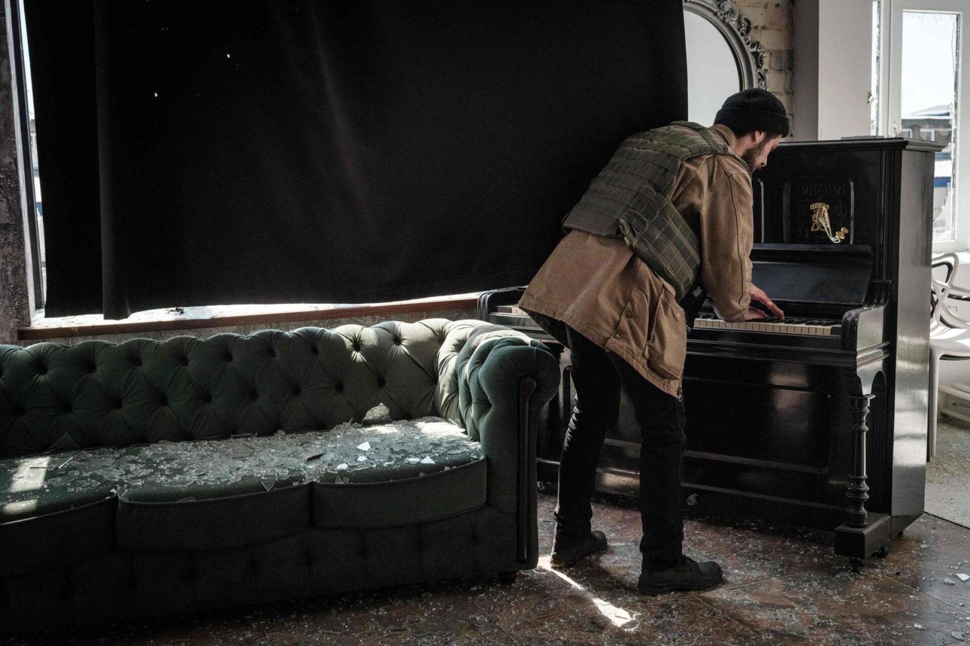 Mies soittaa pianoa hylätyssä valokuausstudiossa Severodonetskissa.