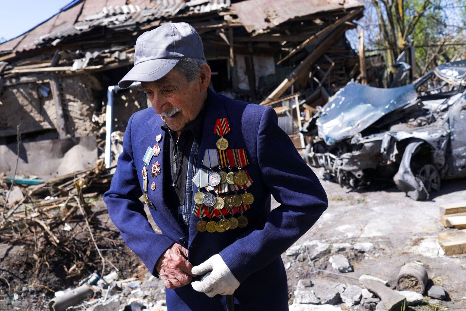 Ivan Lisun, 97, pommitetun talonsa edessä Zolochivissa Harkovan lähellä. Hän on toisen maailmansodan veteraani ja yllään hänellä on takki, jossa ovat ansaitut ansiomerkit.