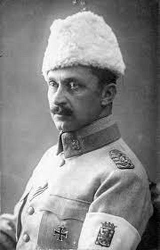 Ratsuväenkenraaliksi ylennetyllä Mannerheimilla on yllään harmaa sotilaspuku, käsivarressaan valkoinen nauha ja päässään valkea karvalakki. Rinnassa kiiltää vasta myönnetty Preussin 1. luokan rautaristi.