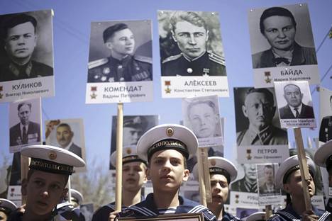 Sevastopolin kadettikoulun oppilaat kantoivat sotaan osallistuneiden venäläisten kuvia Moskovassa lauantaina.