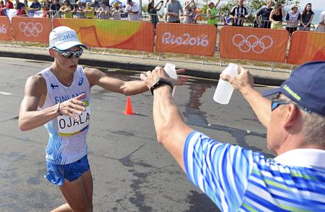 Reima Salonen (oik.) ojentaa suojatilleen Aleksi Ojalalle juotavaa Rion 50 kilometrillä.