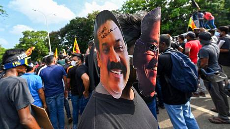 Mielenosoittajat pitelivät Sri Lankan presidentin Gotabaya Rajapaksa (oik.) ja pääministeri Mahinda Rajapaksan kuvista tehtyjä naamioita mielenosoituksessa Colombossa.