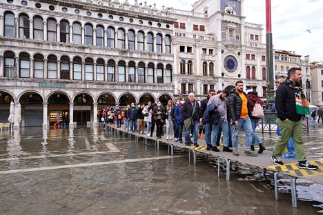 Ihmiset kulkivat väliaikaista rakennelmaa pitkin veden valtaamassa Venetsiassa.