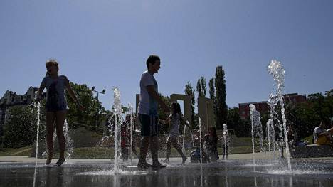 Lapset viilensivät oloaan suihkulähteessä Bulgarian pääkaupungissa Sofiassa lauantaina.