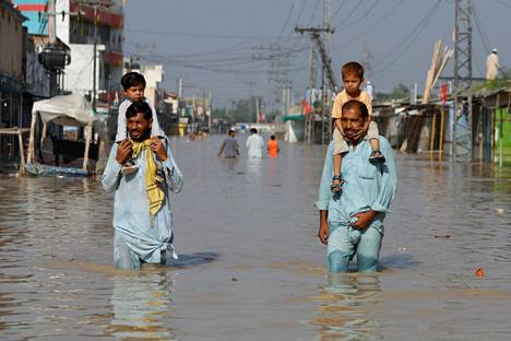 Miehet kantoivat lapsia harteillaan veden valtaamassa Nowsherassa maanantaina.