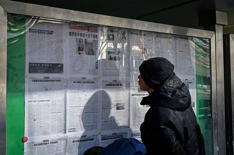 Kiinalaiset lukevat virallisen lehden uutisia Venäjän hyökkäyksestä Ukrainaan.