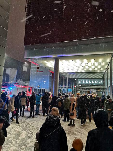 Evakuoidut ihmiset seurasivat tilannetta ulkona lumisateessa.