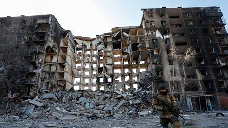 Venäläisjoukkojen sotilas tuhotun asuinrakennuksen edessä Mariupolissa maanantaina.