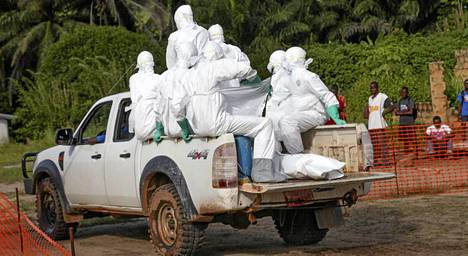 Liberian terveystyöntekijät ovat pukeutuneet suojapukuihin. Työntekijät ovat matkalla hautaamaan Ebolaan kuolleen naisen.