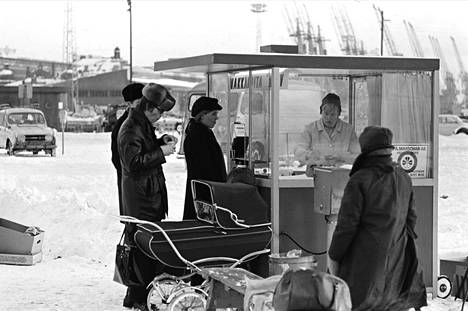 Ihmisiä makkarakojun ympärillä lumisella Kauppatorilla. Kuva vuodelta 1970.