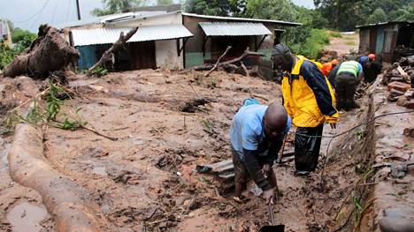 Miehet etsivät myrskyn uhreja Blantyren kaupungissa Malawissa maanantaina 13. maaliskuuta.