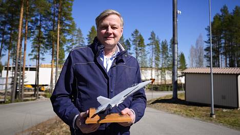 Patrian F-35-hankejohtaja Petri Hepola pitää kädessään Hornetin, Suomen nykyisen hävittäjän pienoismallia