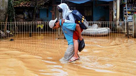 Isä kantaa tytärtään päästäkseen tulvaa pakoon. Kuva otettu 15. maaliskuuta Indonesian Bandungissa.