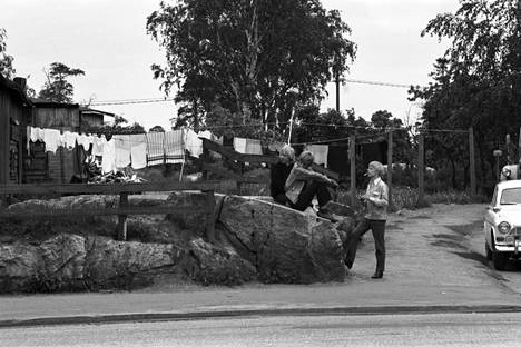 Nuorisoa istuskelemassa kalliolla Selmankadun ja Pasilankadun kulmassa. Taustalla narulla kuivumassa pyykkiä Pasilankatu 22:n pihalla. Kuva vuodelta 1970.