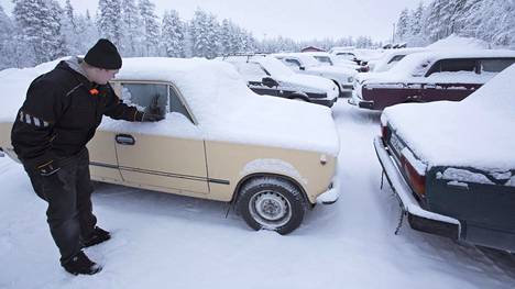Sallan kunnan työntekijä Tuomas Kellokumpu pyyhkii lunta Ladan ikkunasta Sallan hyötyjäteasemalla.