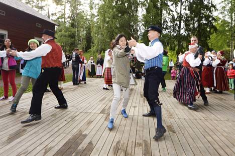 Turisteja ja paikallisia tanssimassa kansantansseja koleassa Seurasaaressa Helsingissä juhannusaattona 2014. 