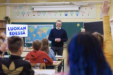 Petteri Orpo (kok) saapuu hymyilevänä luokkahuoneeseen, kunnes huomaa, ettei vierailu olekaan helpoimmasta päästä.