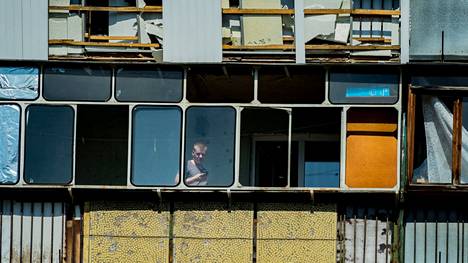 Mies katseli Venäjän yöllisissä iskuissa vahingoittuneen parvekkeensa ikkunoista Kiovassa torstaina.