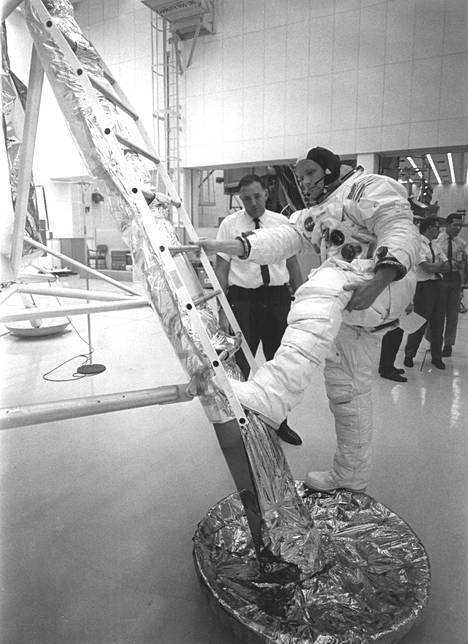 Avaruuspukuunsa pukeutunut Apollo 11 -komentaja Neil Armstrong harjoitteli nousemista kuumoduuli Eaglen tikkaiden alimmalle askelmalle heinäkuussa 1969, viikkoa ennen lähtölaukaisua. Astronauttien työpäivät venyivät ennen Kuu-lentoa usein 14-tuntisiksi. Armstrong ja kuumoduulin lentäjä Buzz Aldrin keräsivät Kuun pinnalta lopulta yli 20 kiloa näytteitä. Komento- ja huoltomoduulin lentäjä Michael Collins odotti Kuu-kävelyn aikana Kuun kiertoradalla.