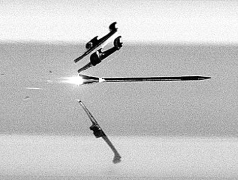 Suurnopeuskameralla otettu kuva näyttää, kuinka ohjausosat irtoavat nuoliammuksesta kanuunan suulla. Ammus läpäisee panssarointia liike-energian voimalla.