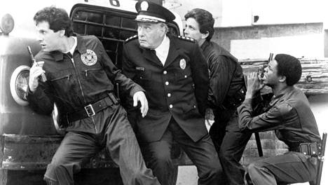 Poliisiopisto-elokuvia tehtiin yhteensä seitsemän kappaletta vuosina 1984–1994. Kuvassa tiukassa tilanteessa ovat vasemmalta Carey Mahoney (Steve Guttenberg), komentaja Eric Lassard (George Gaynes), George Martin (Andrew Rubin) sekä Larvell Jones (Michael Winslow).
