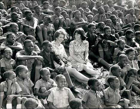 Anne began working in a representative office in her twenties.  Here he sits in Nairobi, Kenya in 1971 to watch a football match surrounded by local orphans.