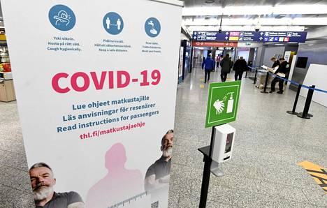  Koronaviruksesta ja matkustamisesta kertova kyltti ja käsien desinfiointipiste Helsinki-Vantaan lentokentällä perjantaina 8. tammikuuta 2021.