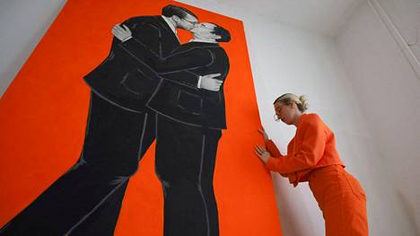 Kosovolainen taiteilija Ermira Murati (oik.) maalauksensa vieressä Pristinassa viime viikolla. Maalauksessa esitetään Kosovon pääministeri Albin Kurti ja Serbian presidentti  Aleksandar Vucic antamassa suudelmaa toisilleen. 