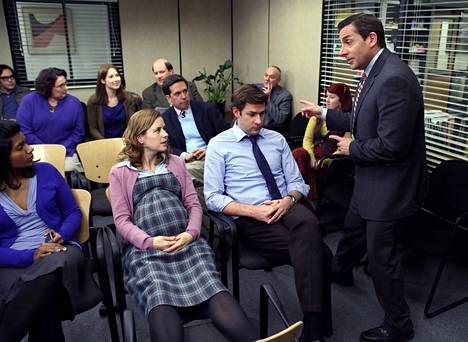 Kelly (Mindy Kaling, left), Pam (Jenna Fischer) and Jim (John Krasinski) front row in The Office series The Office.  Michael Boss (Steve Carell) is working as usual.