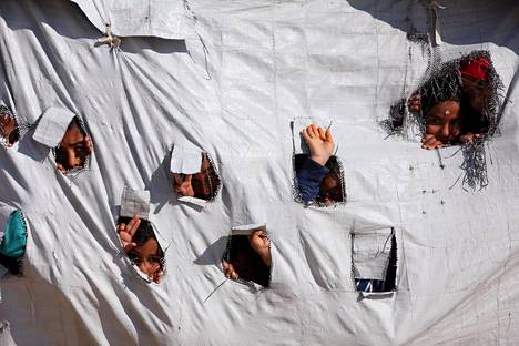 Lapset kurkistelivat teltan seinissä olevista rei’istä al-Holin leirillä huhtikuussa.