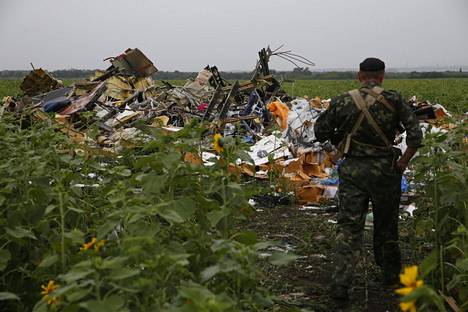 Itä-Ukrainan separatisteihin kuuluva mies katsoo Malaysia Airlinesin pudonnutta konetta.