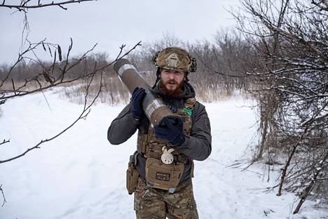 Ukrainan 80. ilmarynnäkköprikaatin sotilas kantaa yhdysvaltalaisen M119-haupitsin ammusta tuliasemaan lähellä Bahmutin kaupunkia 16. helmikuuta 2023.