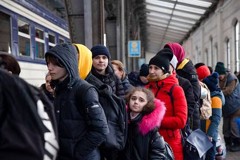 Ihmiset odottavat jonossa pääsyä Puolaan menevään junaan Lvivin rautatieasemalla.