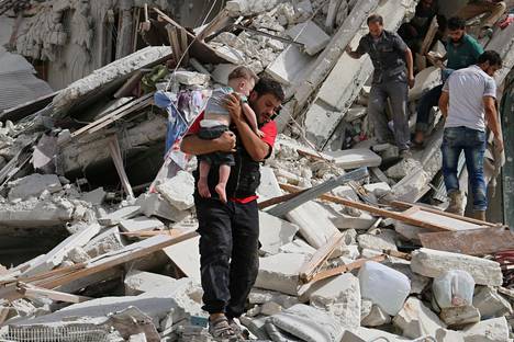 Mies kantoi ilmaiskuissa loukkaantunutta lasta Aleppossa viime viikolla. Unicefin arvion mukaan kaupungin itäisissä osissa on jumissa 100000 lasta.