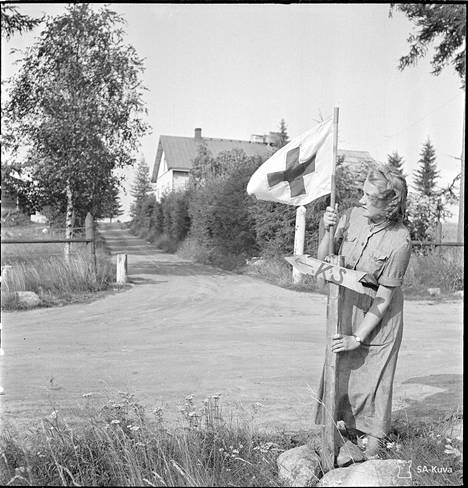 Lotta kiinnittää kenttäsairaalan paikkaa osoittavan lipun tien varteen Tolvajärvellä 1941.