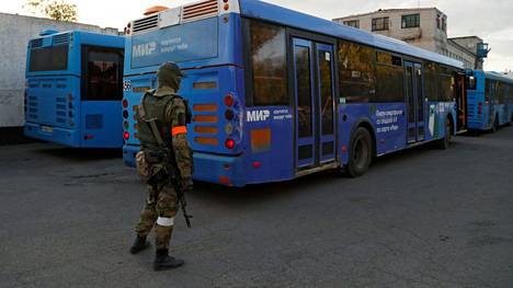Azovstalin sotilaiden evakuointiin käytettyjä sinisiä busseja Olenivkassa tiistaina. Etualalla punaista nauhaa käsivarressa pitävä Venäjän-mielisten joukkojen taistelija.