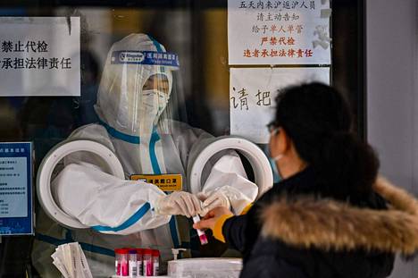 Terveydenhuollon työntekijä otti kansalaiselta vastaan koronavirusnäytteen Shanghaissa 8. joulukuuta. Kiina oli edellisenä päivänä ilmoittanut koronatoimien löysäämisestä.